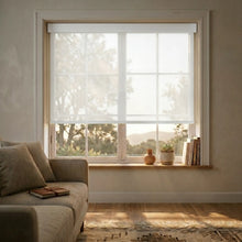 Load image into Gallery viewer, A bright, minimalist living room featuring crisp White Signature solar roller shades with 5% openness, providing a clean architectural look and energy-efficient heat reduction.
