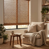 Cordless Woven Wood Shades effortlessly filter natural light, complementing the serene atmosphere in this peaceful study space with a chair and tasteful decor.