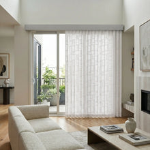 Load image into Gallery viewer, Signature Collection Fabric Vertical Blinds in crisp white seamlessly integrate with the sliding glass door, showcasing a serene outdoor oasis featuring lush greenery and a wooden bench.
