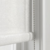Macro close-up of the textured white Luxe fabric and the durable metallic beaded chain mechanism of the blackout roller shade
