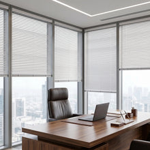 Load image into Gallery viewer, Custom window treatments: White (White Satin) Classic Cordless 6g Aluminum Mini Blinds shown in a cozy living room, offering lightweight yet sturdy window coverage.
