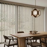 Natural sunlight hits the White Signature Pvc Vertical Blinds in this modern living space, blocking out harsh glare while maintaining a clean aesthetic.