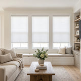 Simplistic Cordless Pleated Shades in pure white harmonize with the room's serene atmosphere, allowing natural light to filter through while maintaining a sense of calm, amidst a stylish arrangement of furniture and decorative accents.
